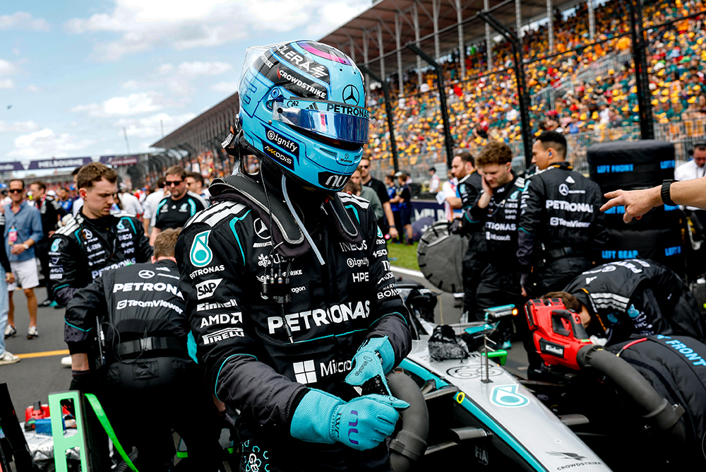 Formula 1 driver climbing into the car on the starting grid surrounded by the team.